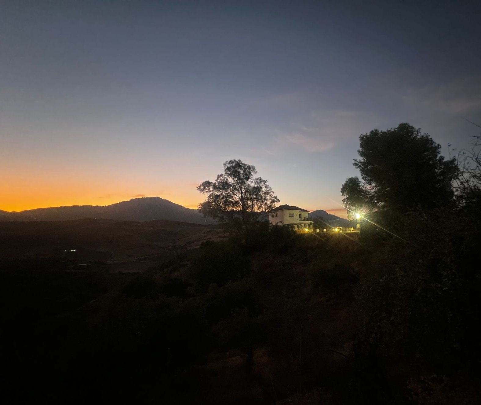 The Ridge property silhouetted against a sunset above the Málaga mountains