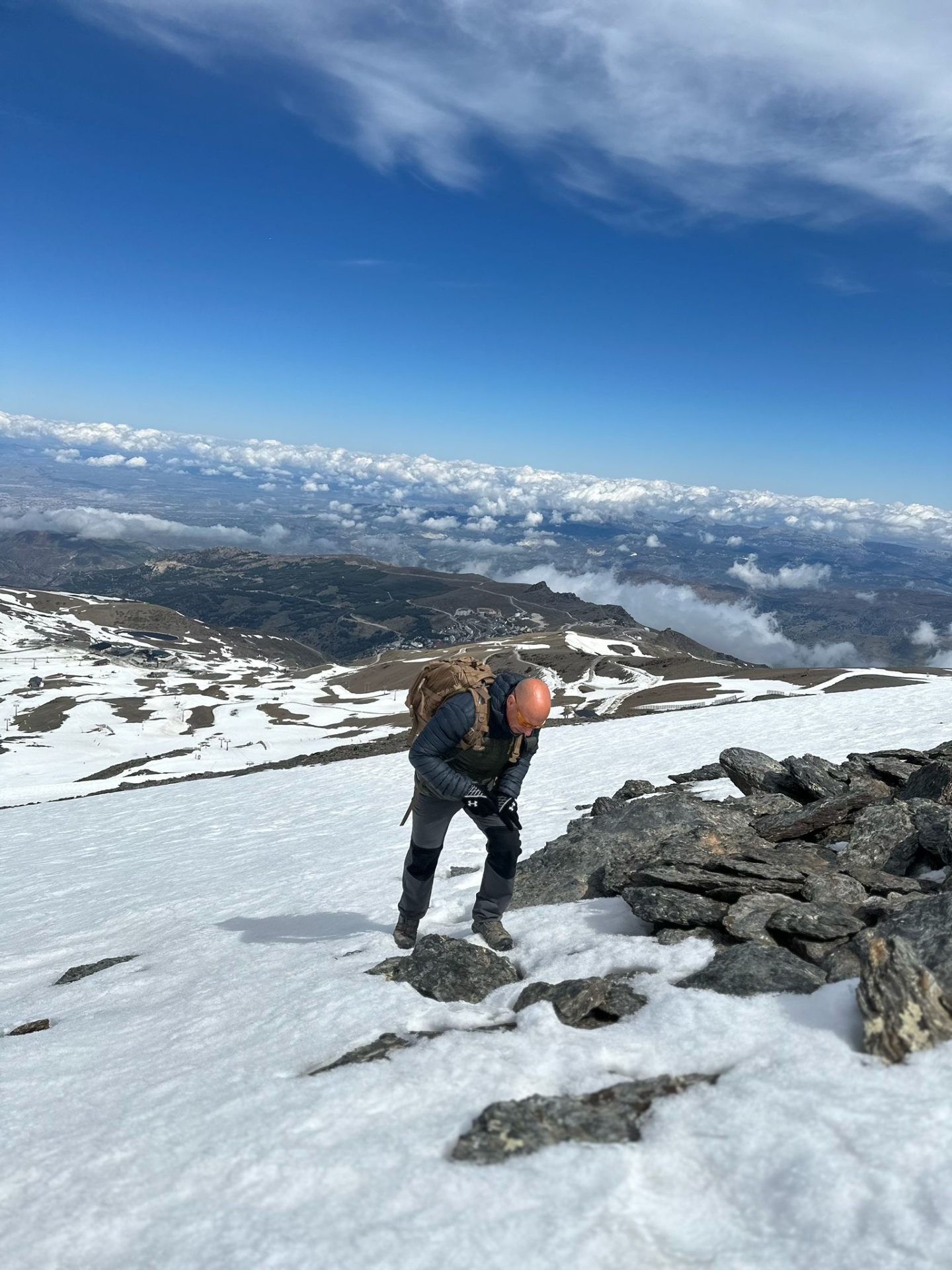 A climber above the clouds in the Sierra Nevada, snow underfoot