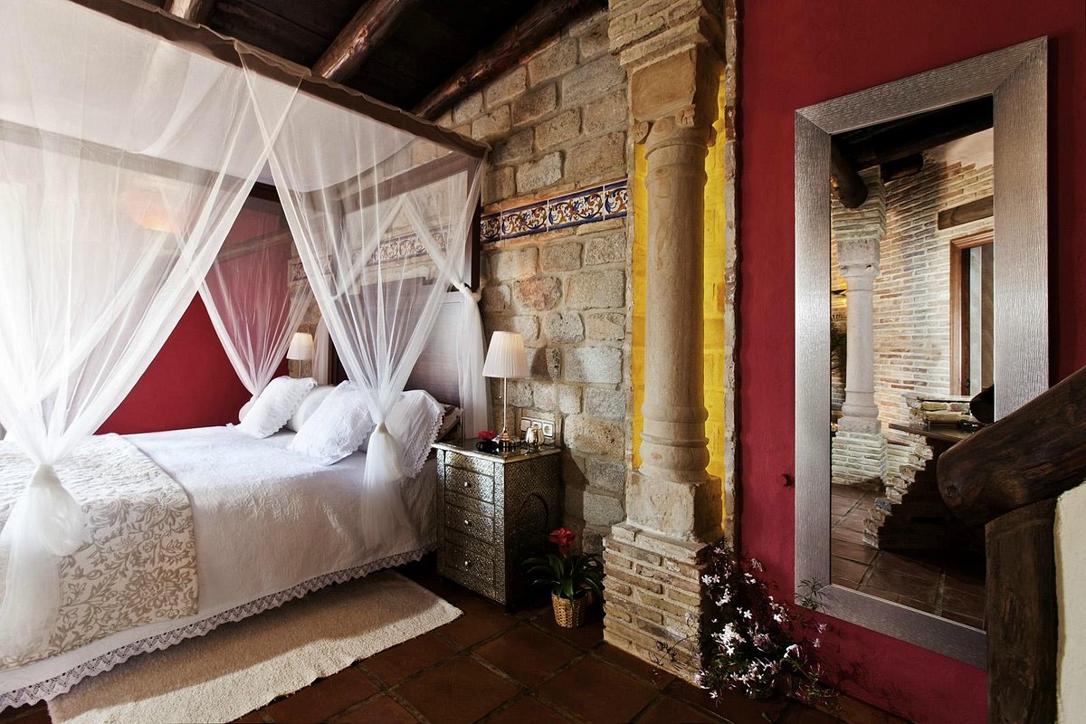 A romantic room with a canopied bed, stone walls and warm colour